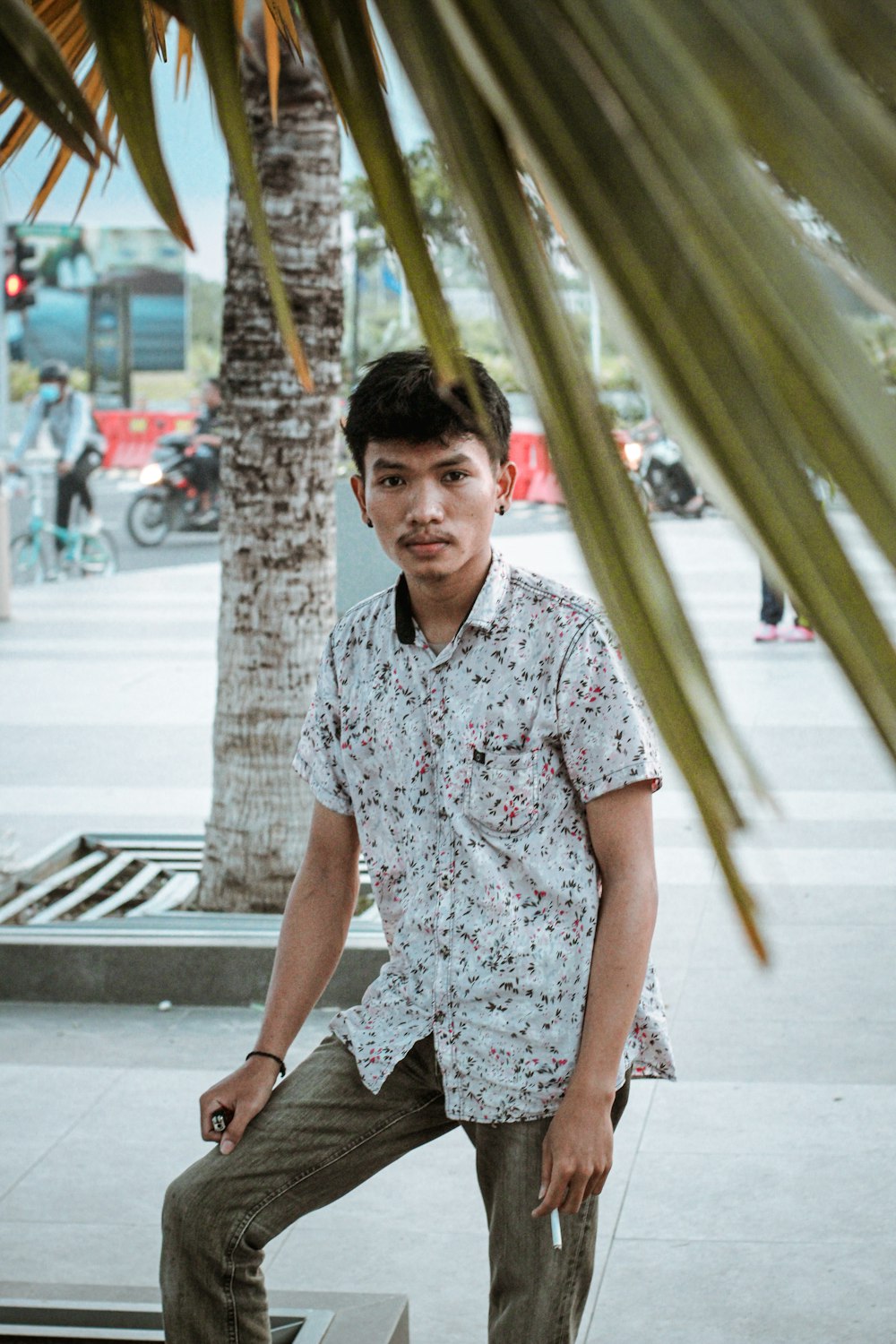 a man sitting on a bench next to a palm tree