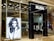 The entrance of a modern hair salon named Rush features sleek glass doors. Inside, the salon is stylishly presented with black chairs and lit mirrors. A large monochrome advertisement poster displays a model with voluminous hair, enhancing the salon's chic interior.