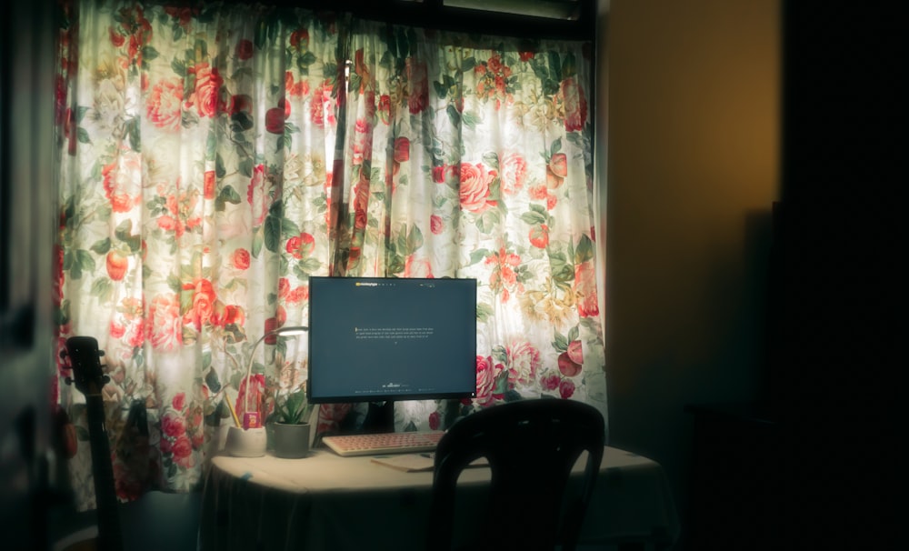 a computer monitor sitting on top of a desk in front of a window