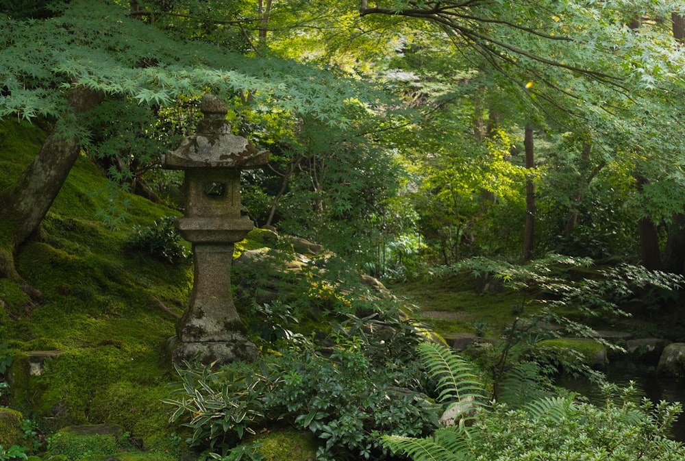 a stone lantern in the middle of a lush green forest