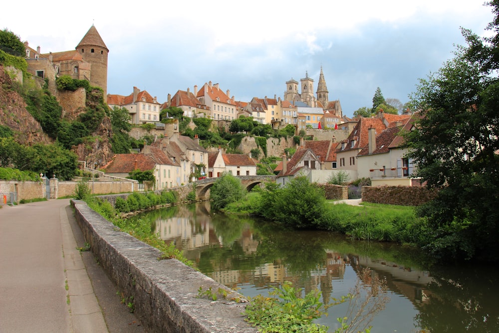 a river running through a village next to a lush green hillside