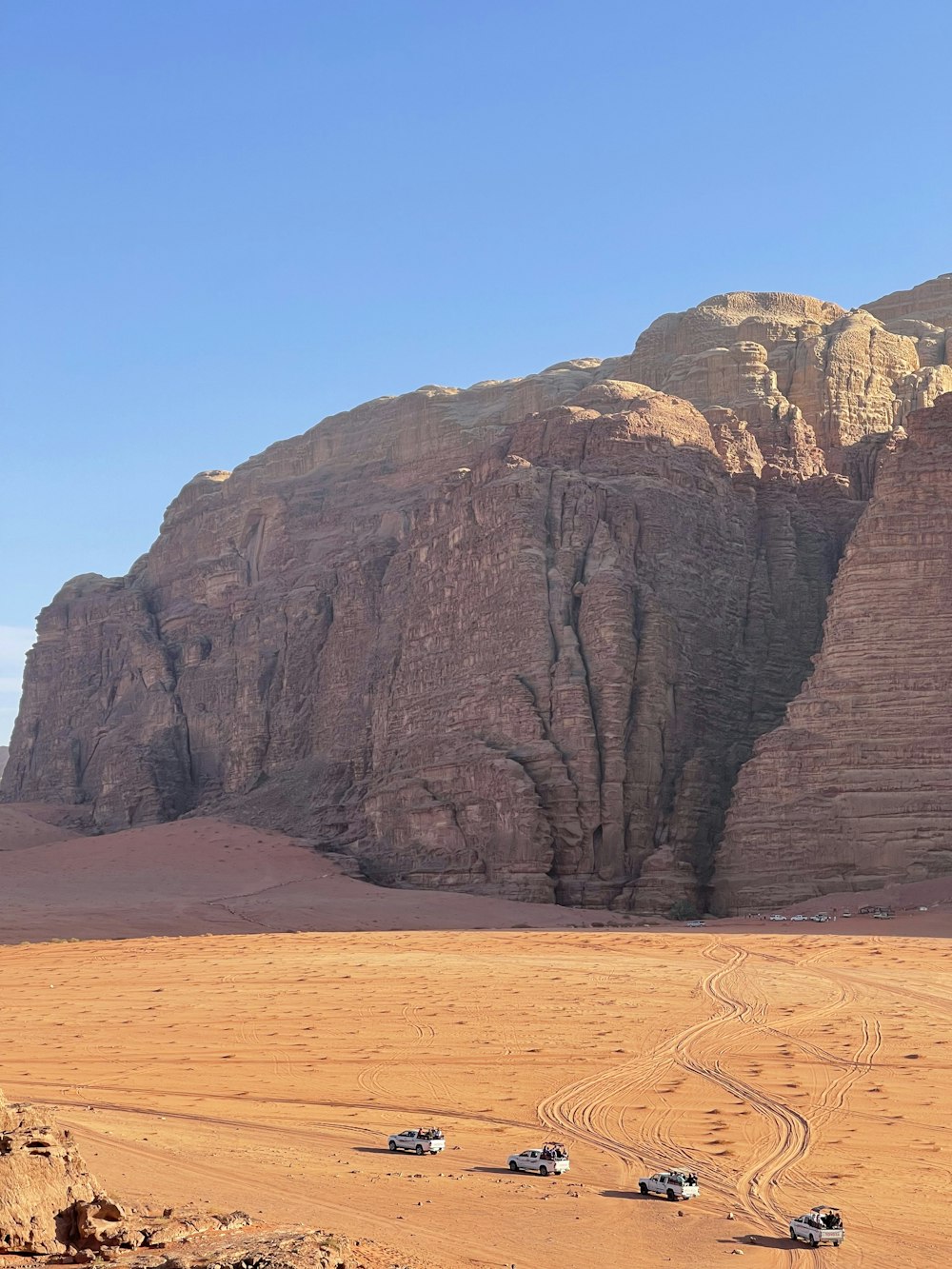 a group of four vehicles driving through a desert