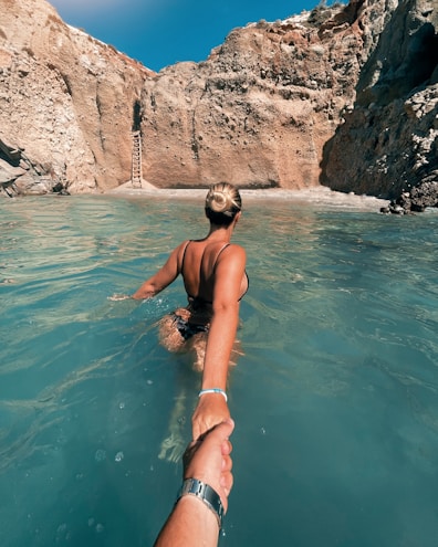 a man and a woman are holding hands in the water