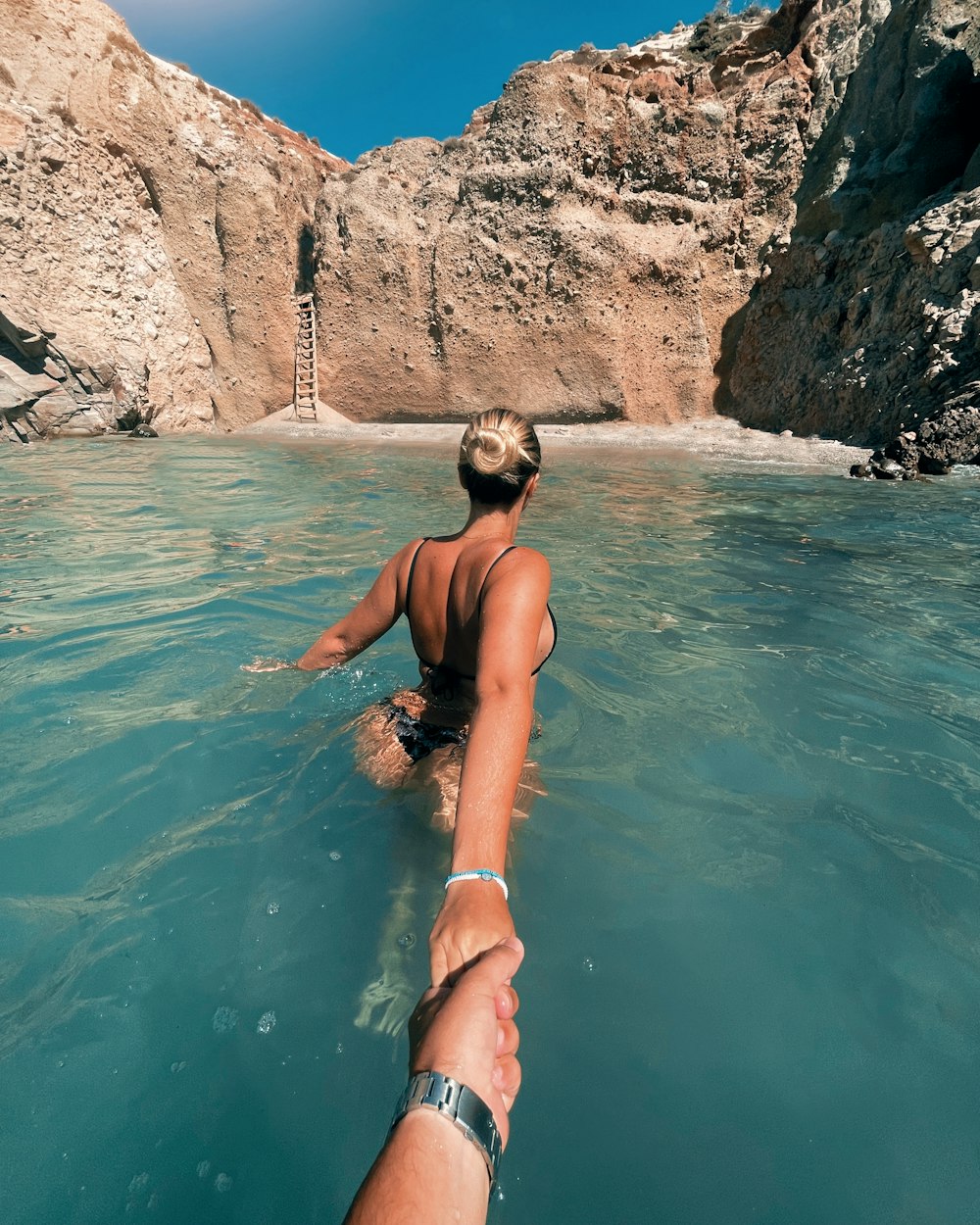 a man and a woman are holding hands in the water