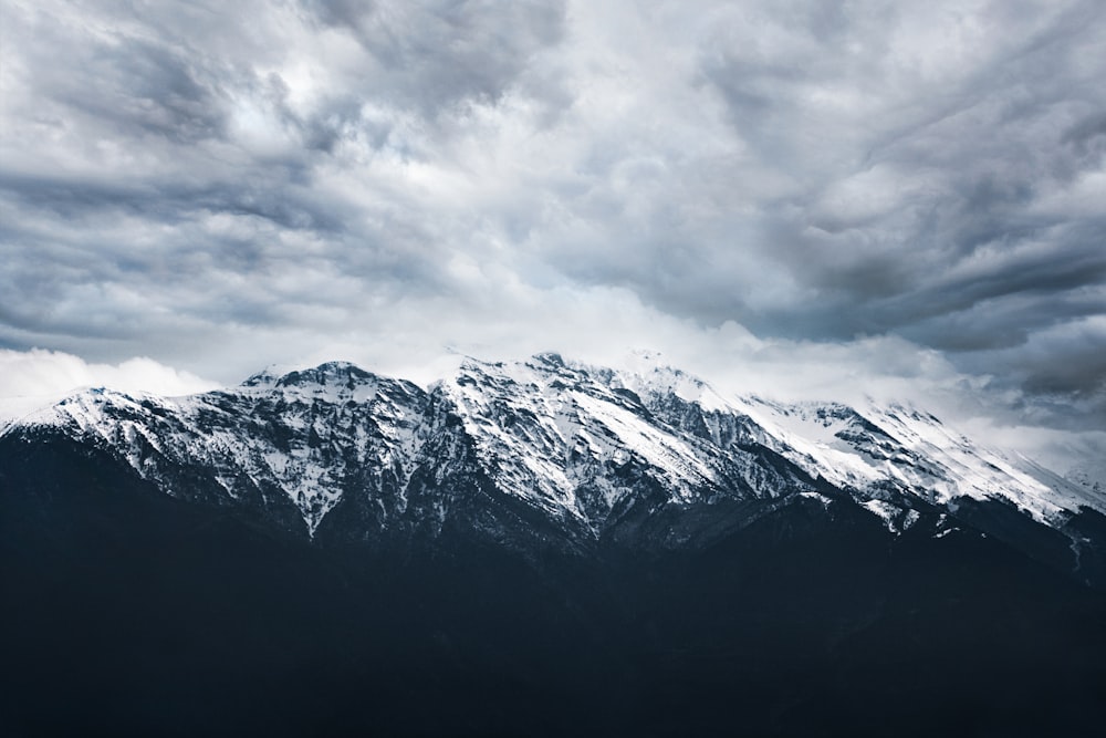 a large mountain covered in snow under a cloudy sky