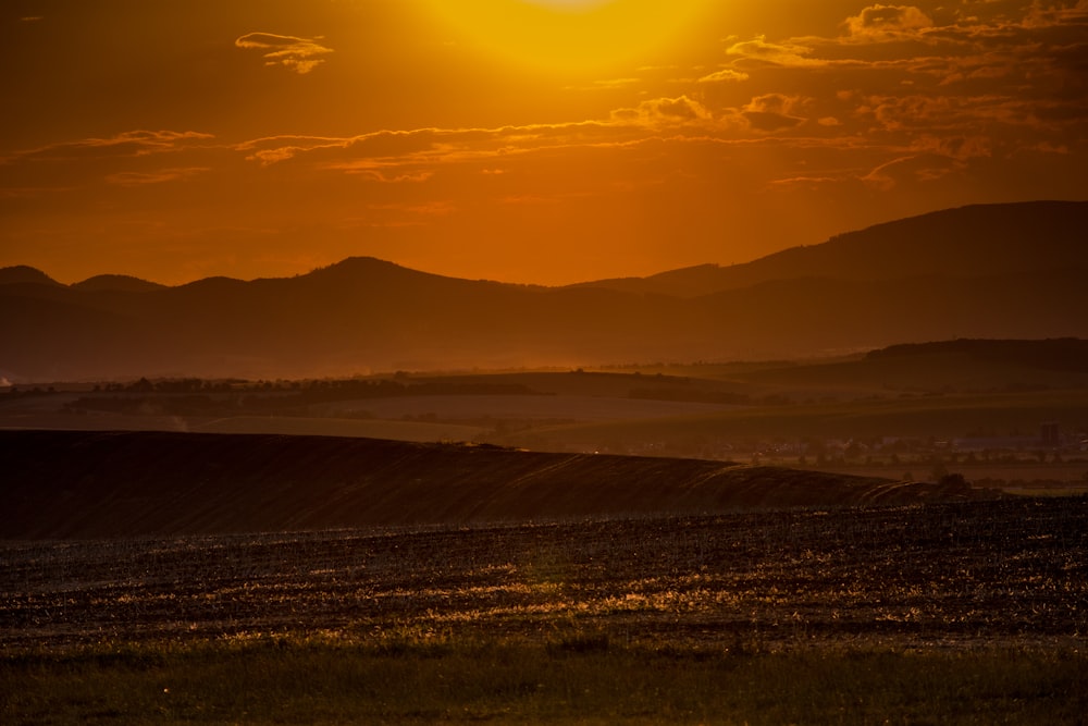 the sun is setting over the mountains in the distance