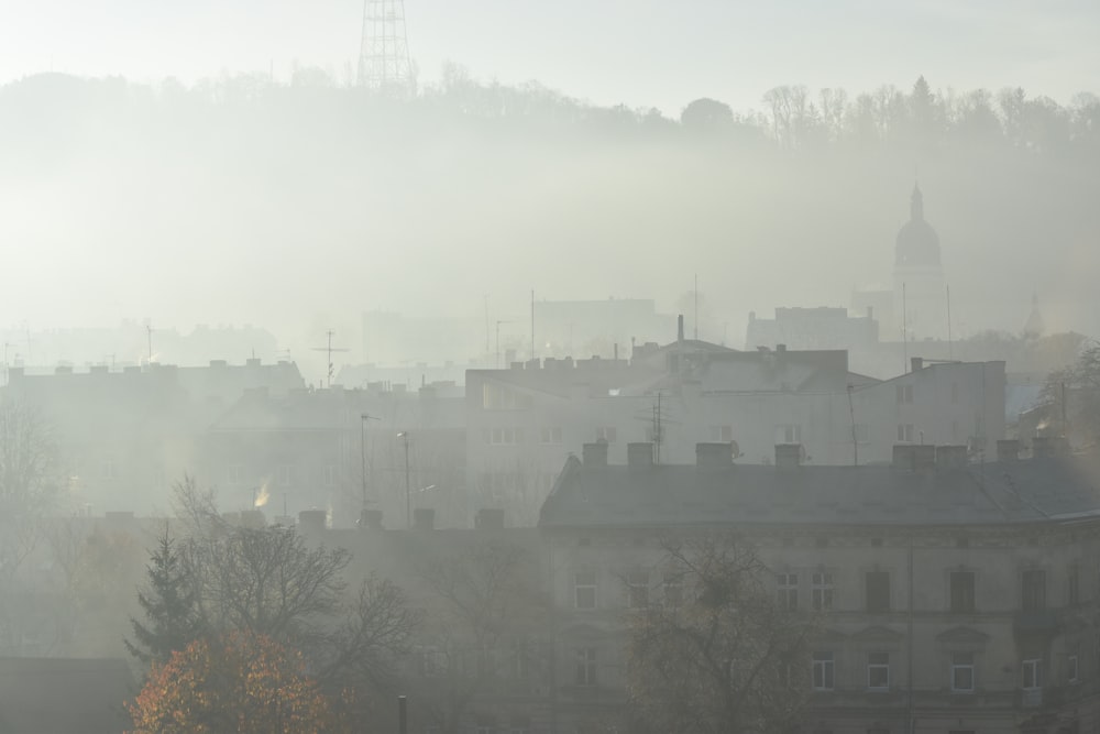 a foggy city with a clock tower in the distance