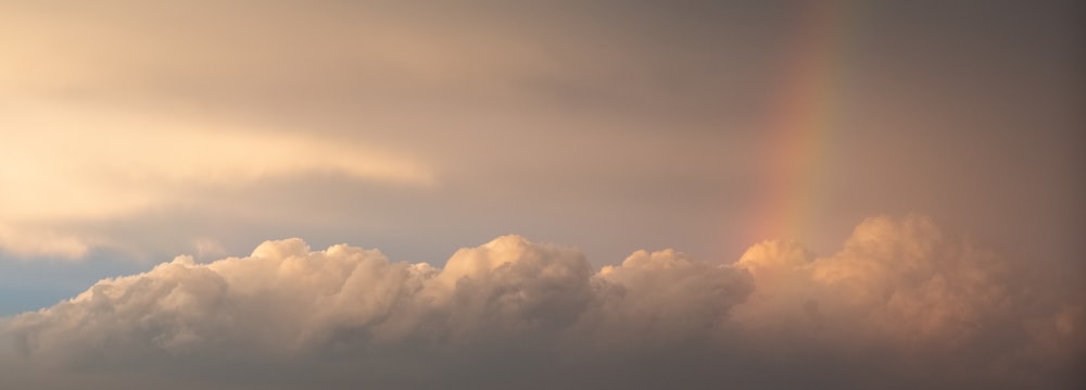a rainbow in the sky with clouds in the background