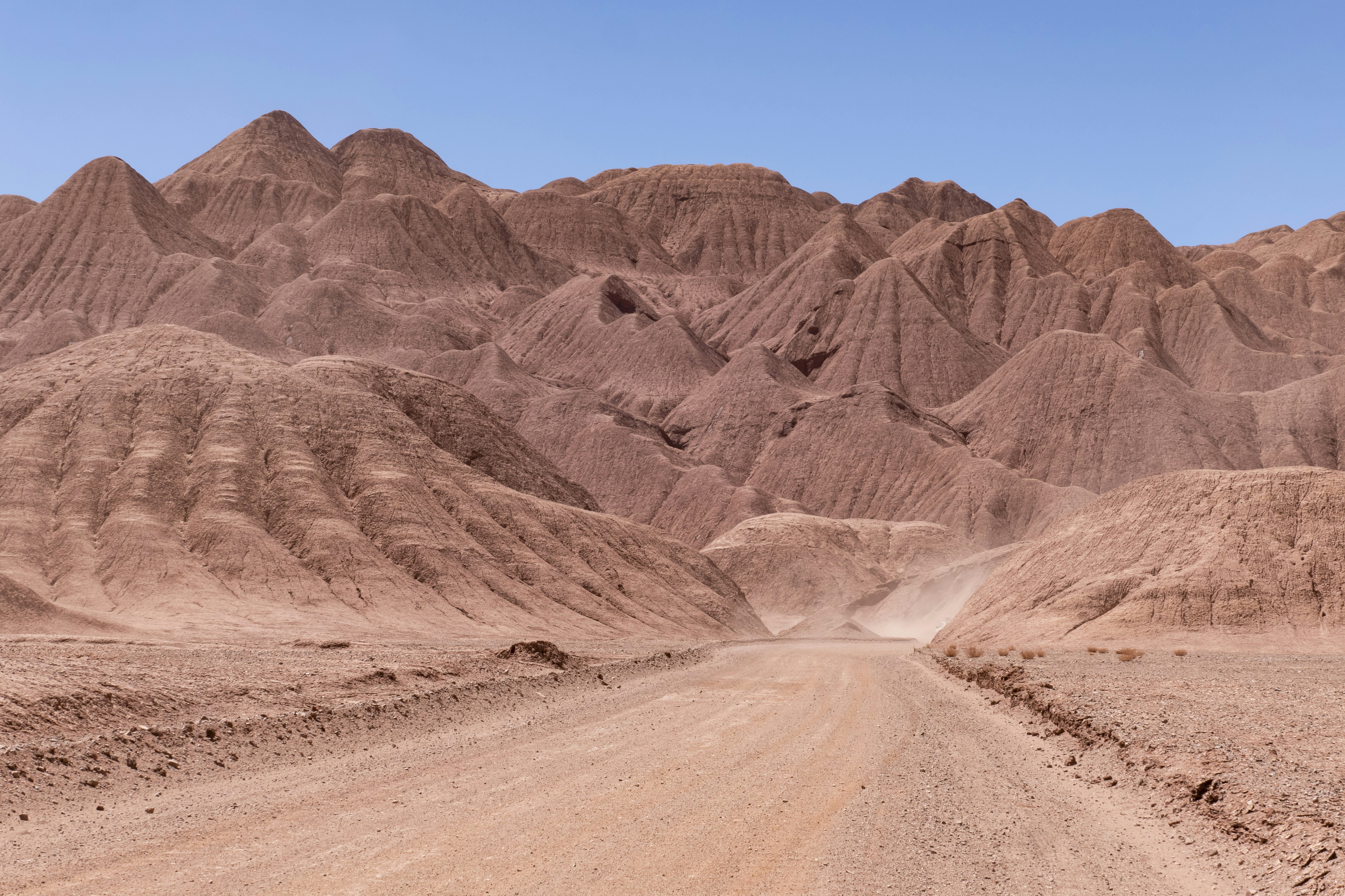 a dirt road in the desert with mountains in the background