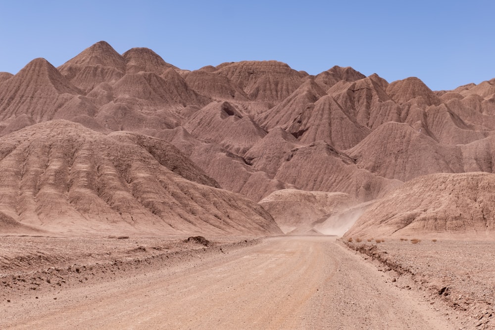 a dirt road in the desert with mountains in the background
