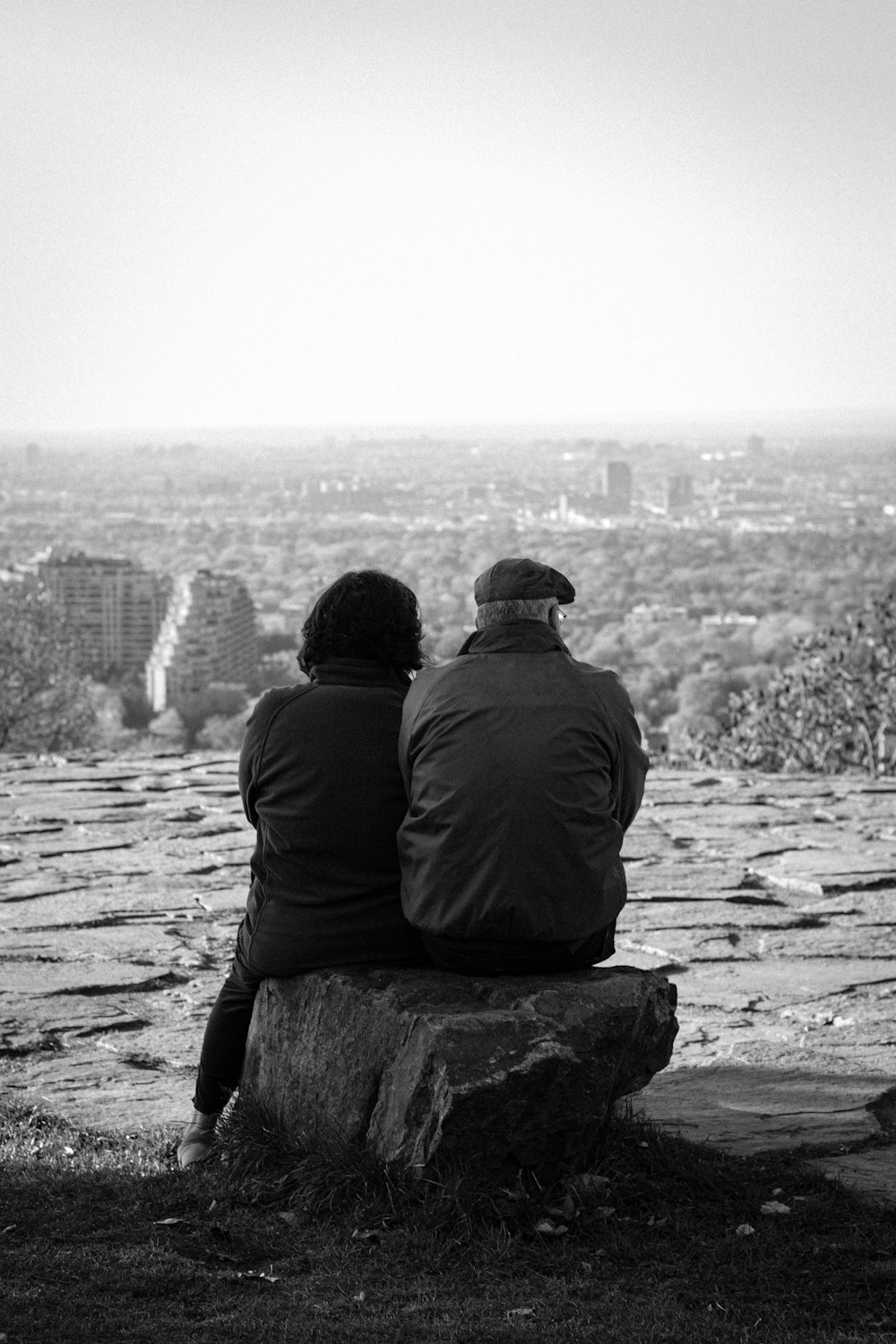 a couple of people sitting on top of a rock