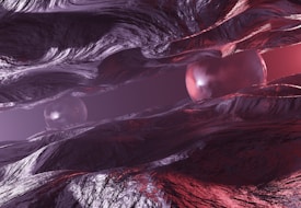 A surreal, abstract scene featuring glossy, metallic textures forming fluid, wave-like structures. Two reflective spheres are nestled among the undulating forms, with a mixture of purple and red hues casting an eerie glow throughout the composition.