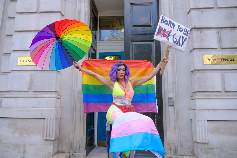 a woman holding a rainbow flag and a rainbow umbrella