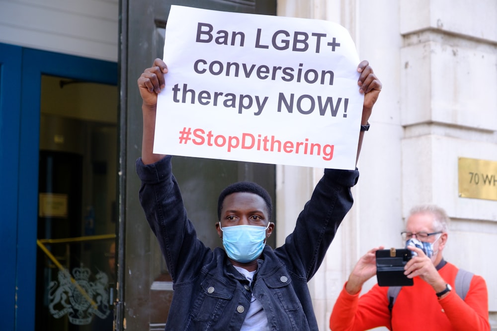 a person holding a sign with a face mask on