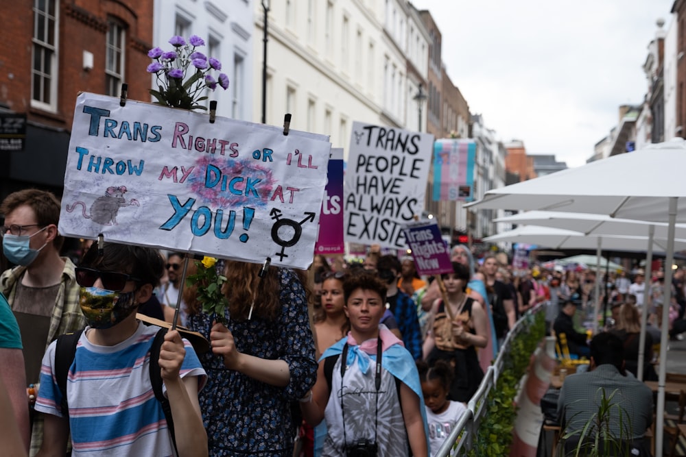 a group of people walking down a street holding signs