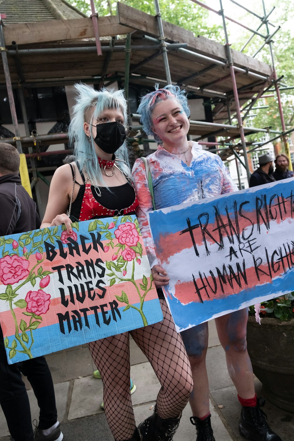 a couple of women standing next to each other holding signs