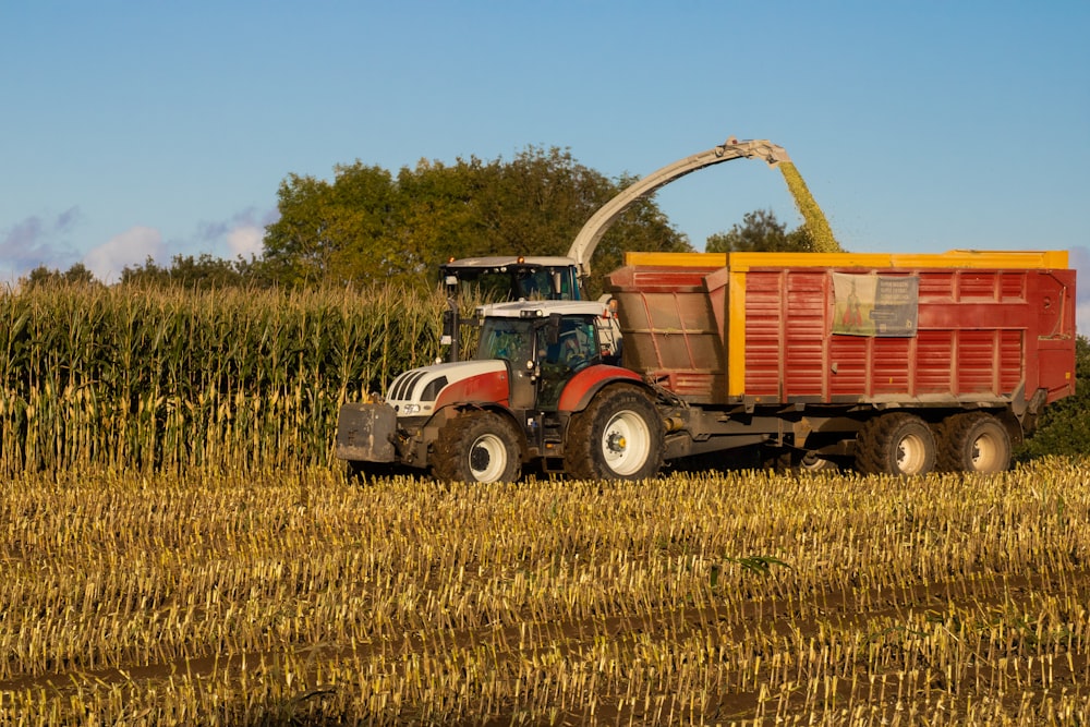 a red and yellow truck driving through a corn field