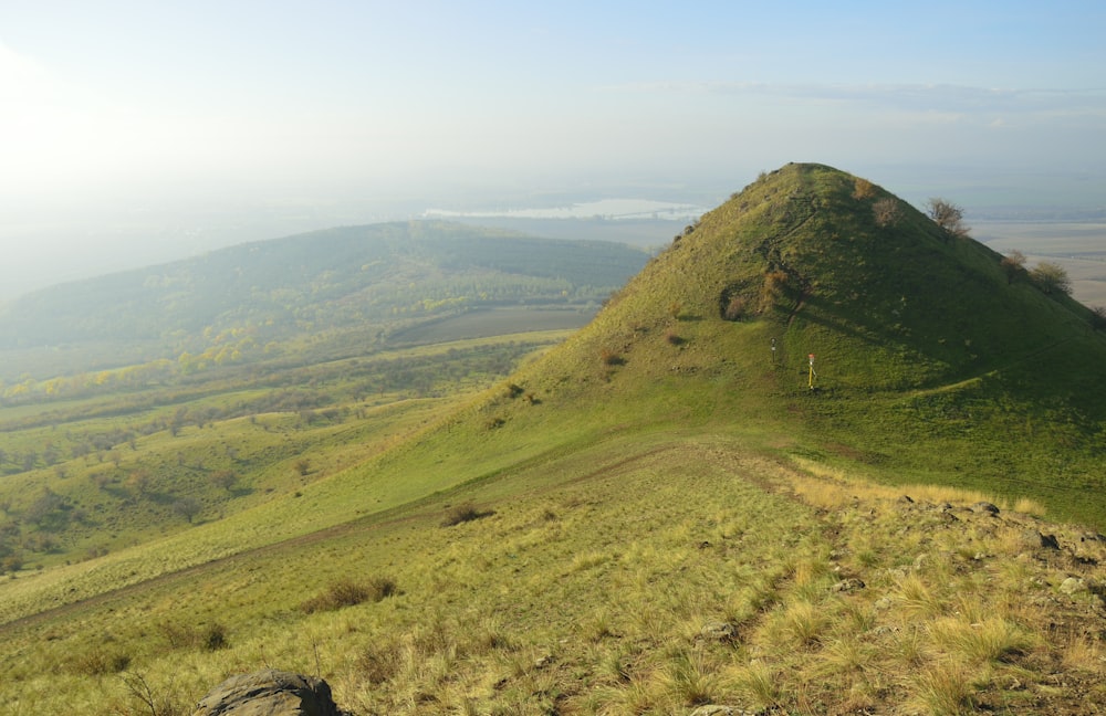 a grassy hill with a large rock in the foreground