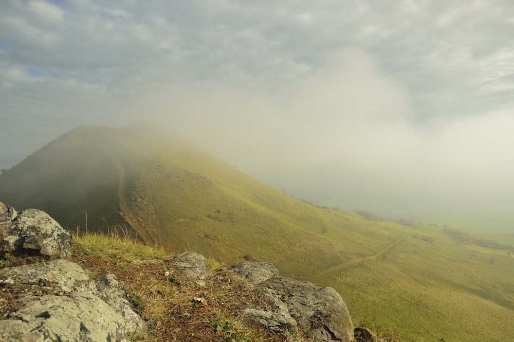 a grassy hill with rocks and grass on top of it