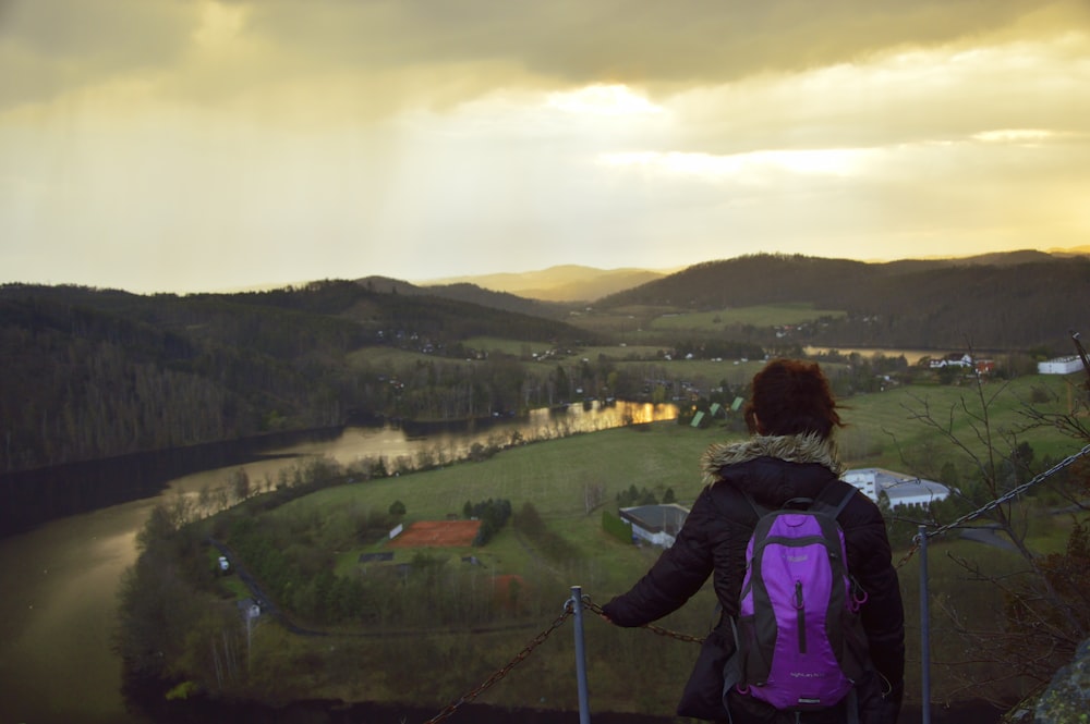 a woman with a backpack standing on top of a hill