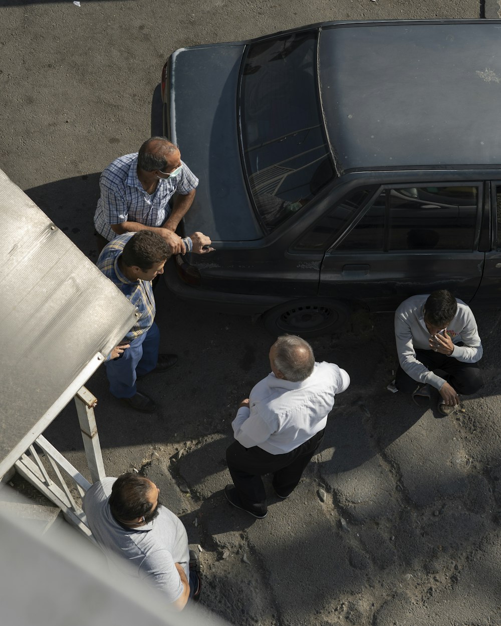 a group of men standing around a car