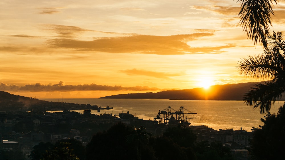 the sun is setting over a city and a body of water