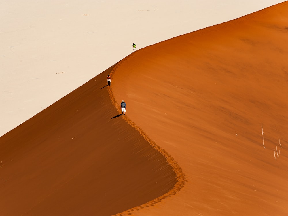 two people walking up a sand dune in the desert