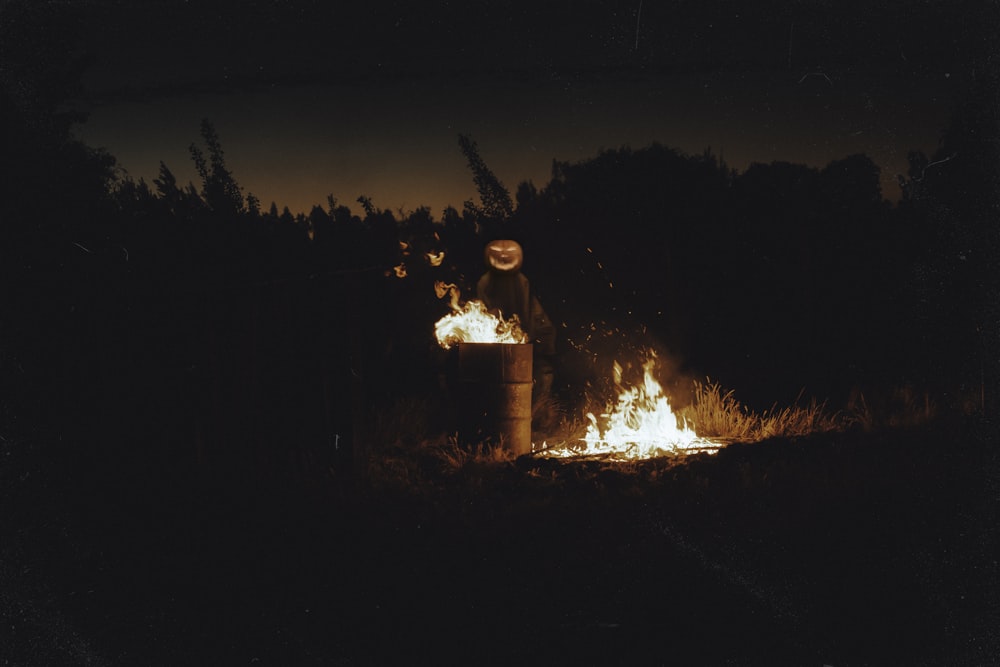 a person standing next to a fire in the dark