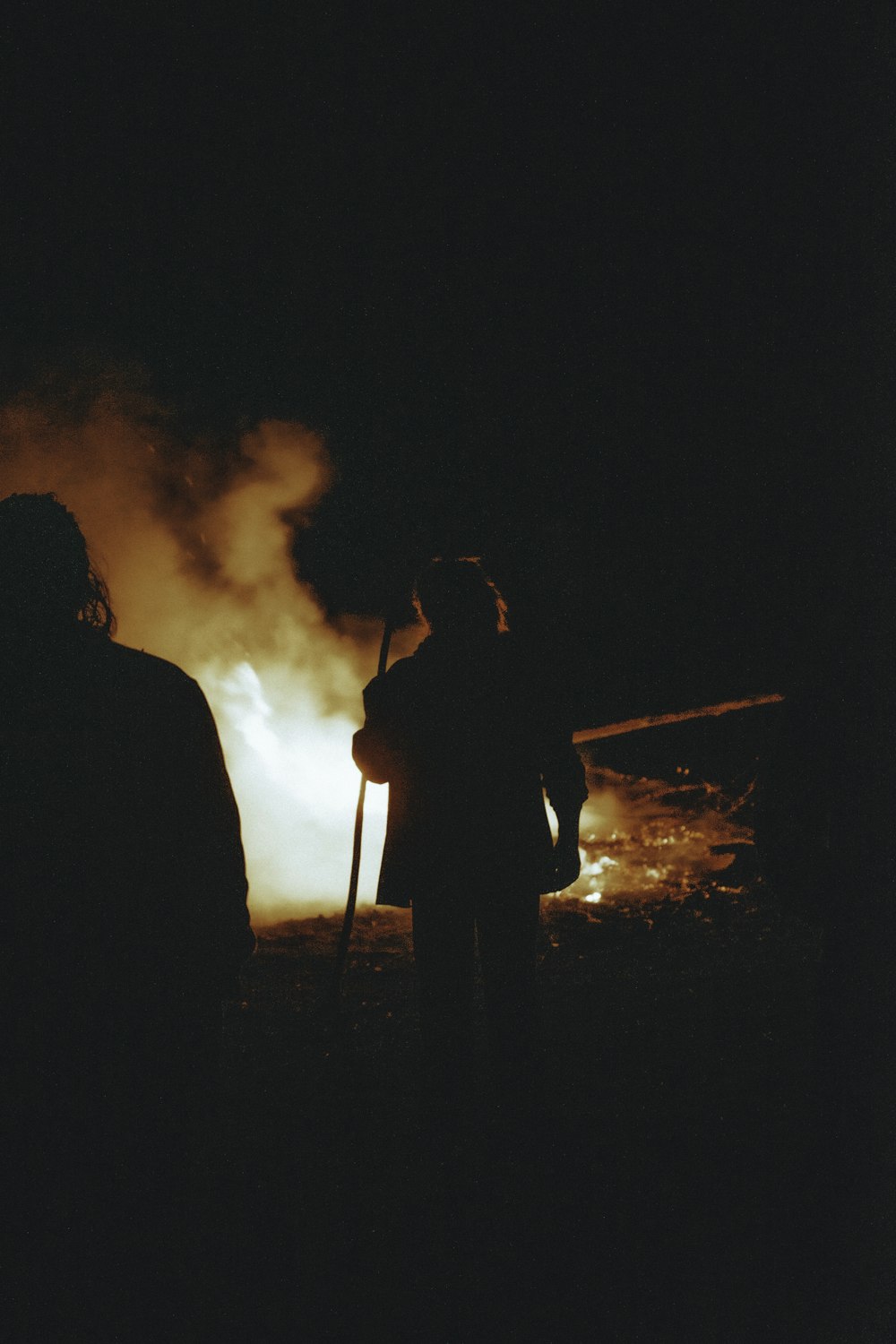 a couple of people standing next to a fire