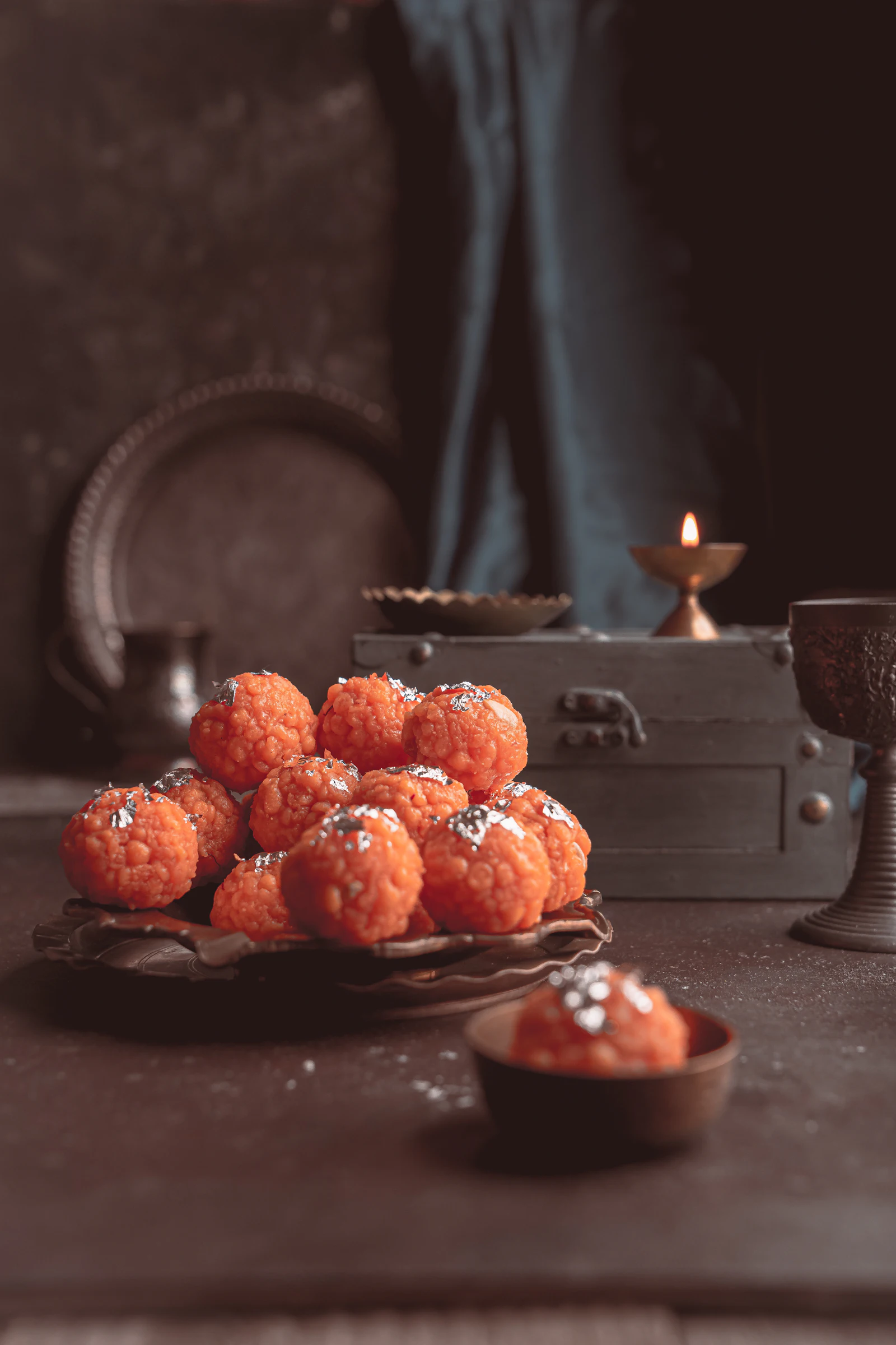Motichoor laddoos beside a lit diya