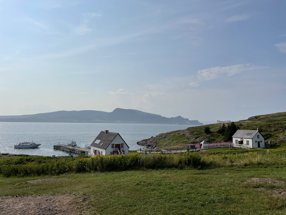 a house sitting on top of a lush green hillside next to a body of water