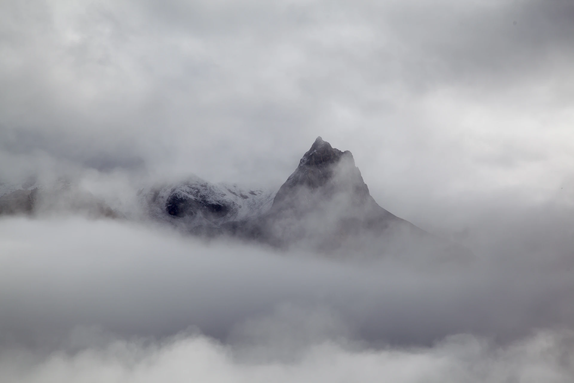 a mountain covered in fog and clouds on a cloudy day