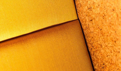 A close-up of textured fabric highlighted by bold yellow accents and deep shadows.