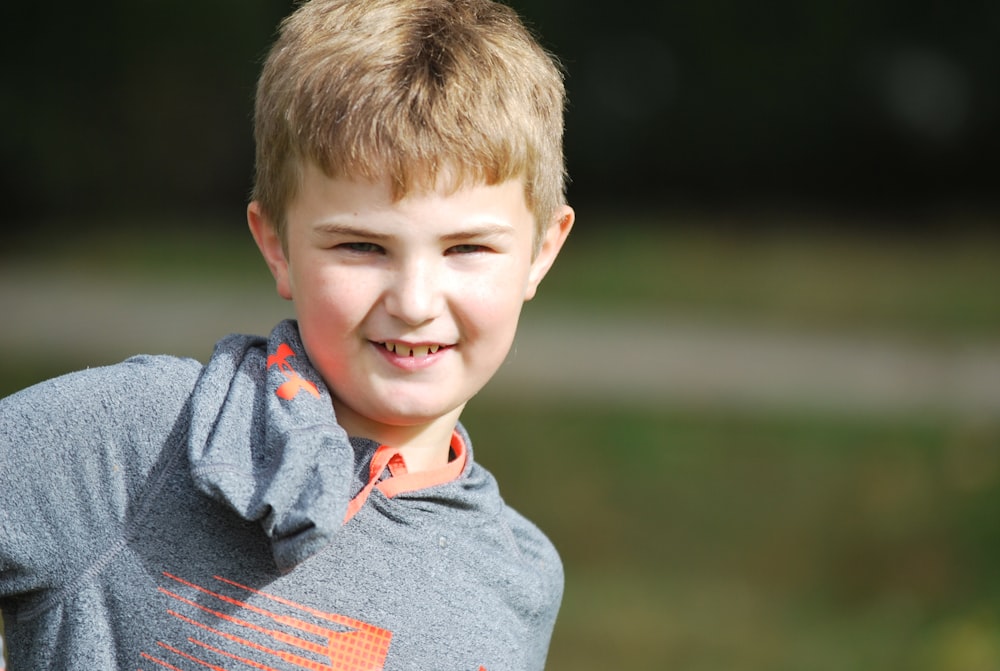 a young boy in a gray and orange shirt