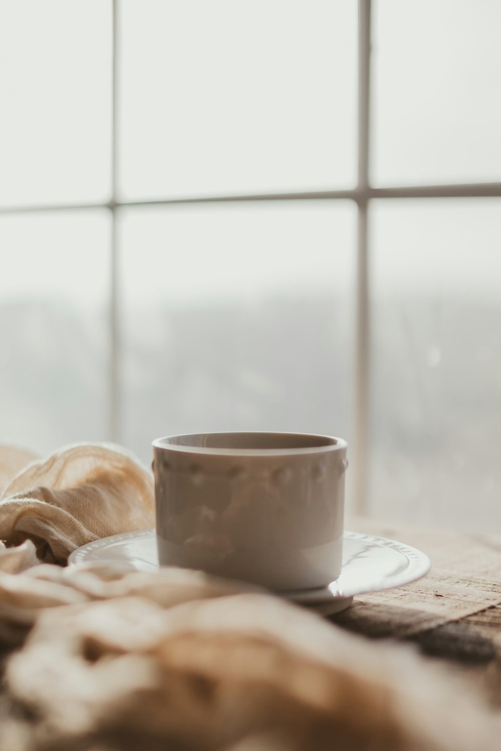 a coffee cup sitting on top of a table next to a window