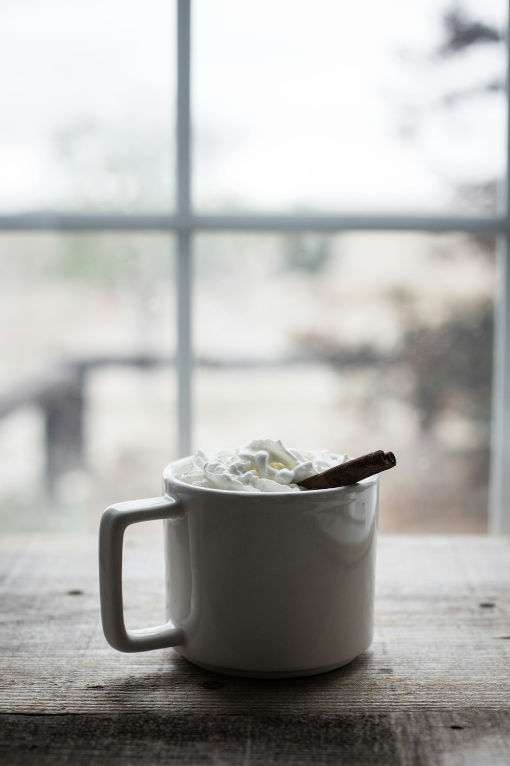 a cup of whipped cream with a cinnamon stick sticking out of it