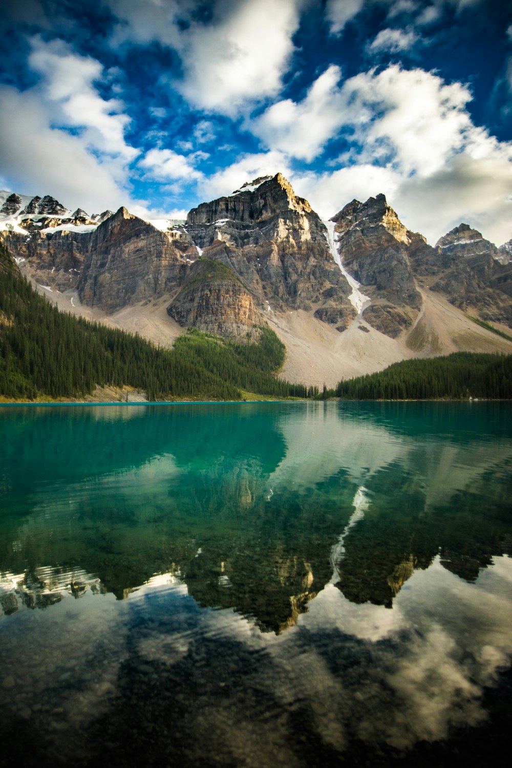 a lake surrounded by mountains under a cloudy sky