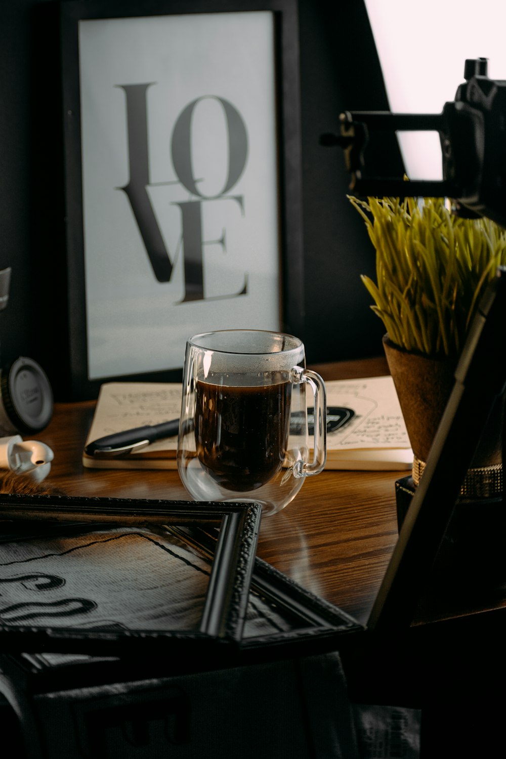 a glass of coffee sitting on top of a wooden table