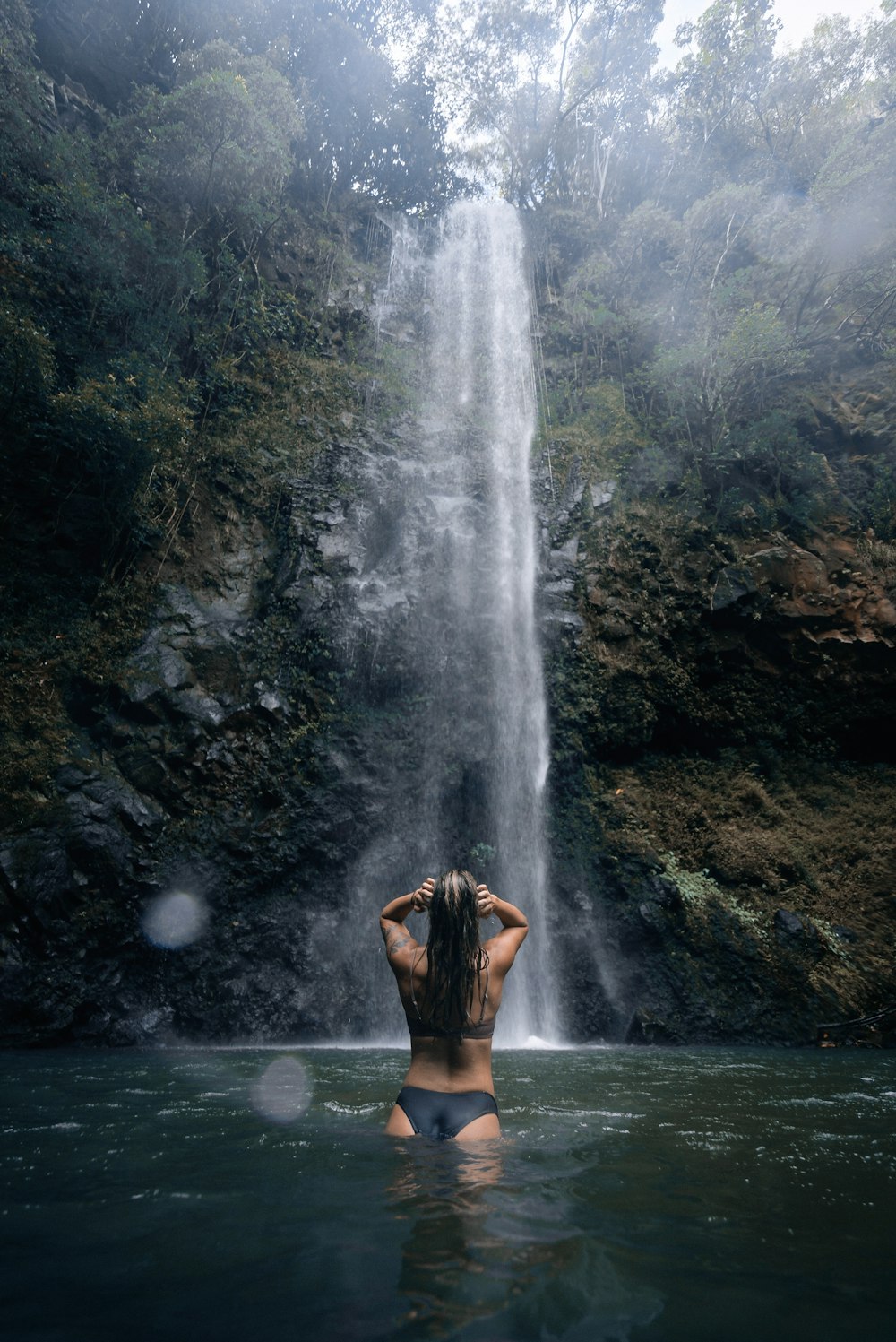 Una donna in piedi nell'acqua di fronte a una cascata