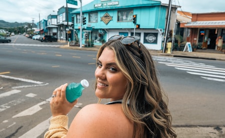 a woman standing on the side of a road holding a cup