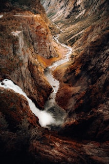 A winding river cutting through a deep canyon with vibrant autumn foliage