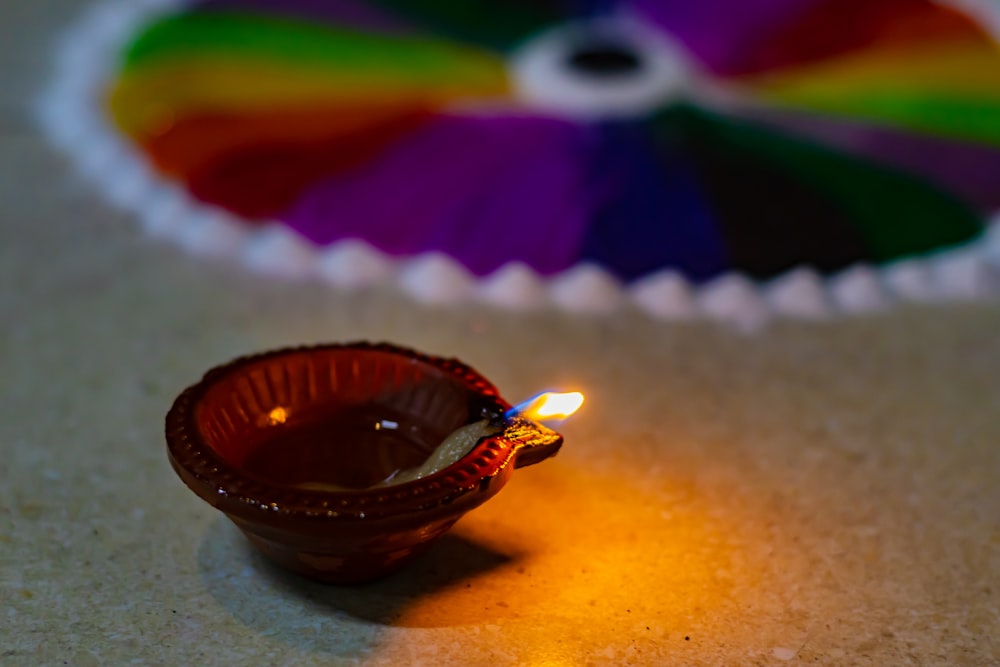 a small brown bowl with a lit candle in it