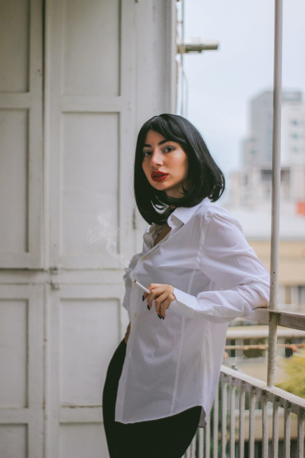 a woman in a white shirt smoking a cigarette