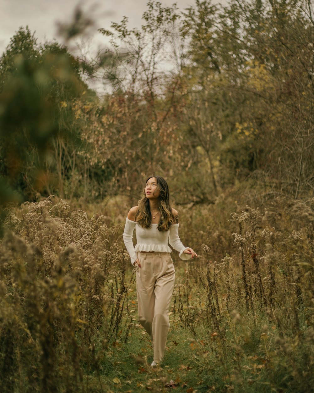 a woman walking through a field of tall grass