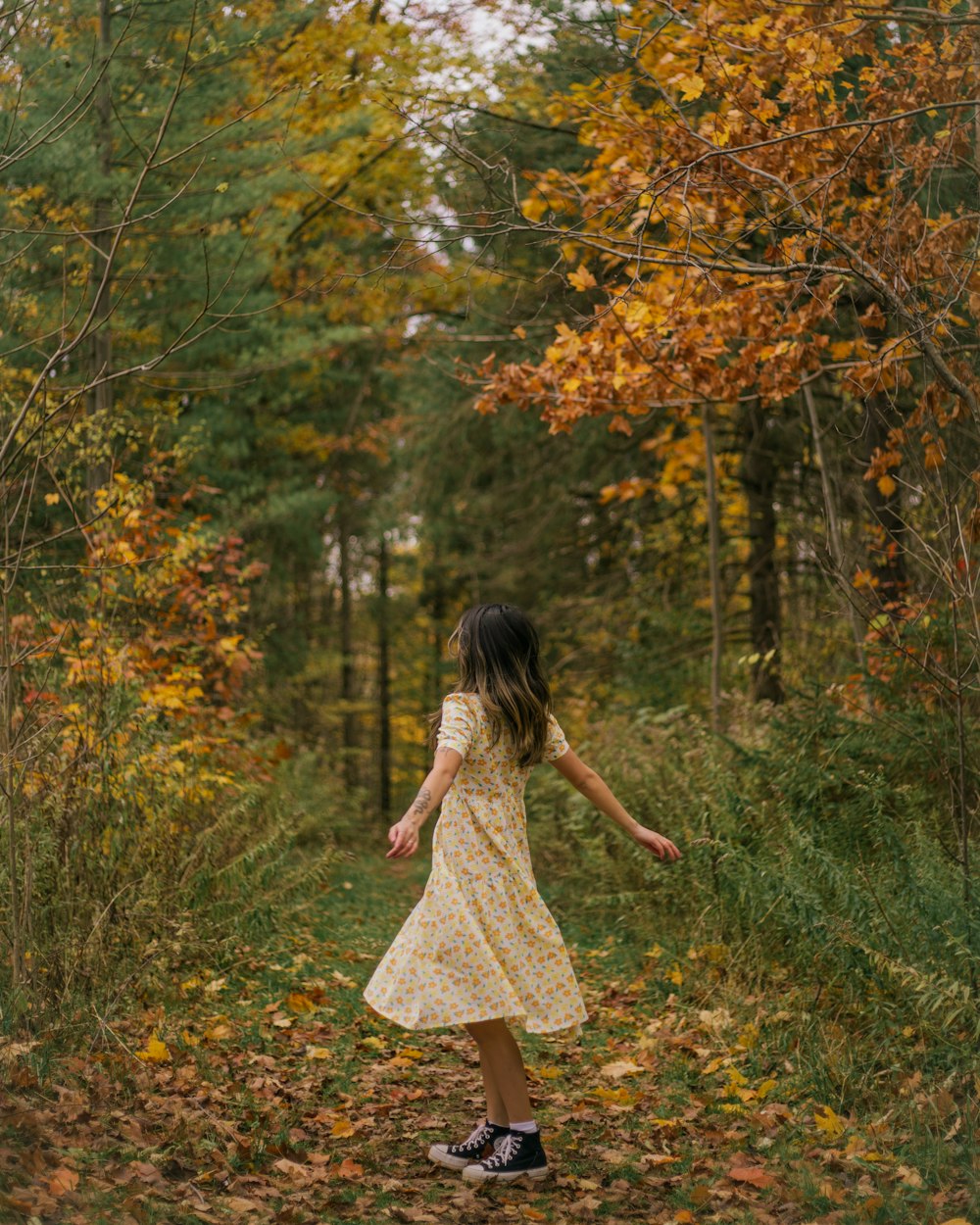 a little girl in a yellow dress is walking through the woods