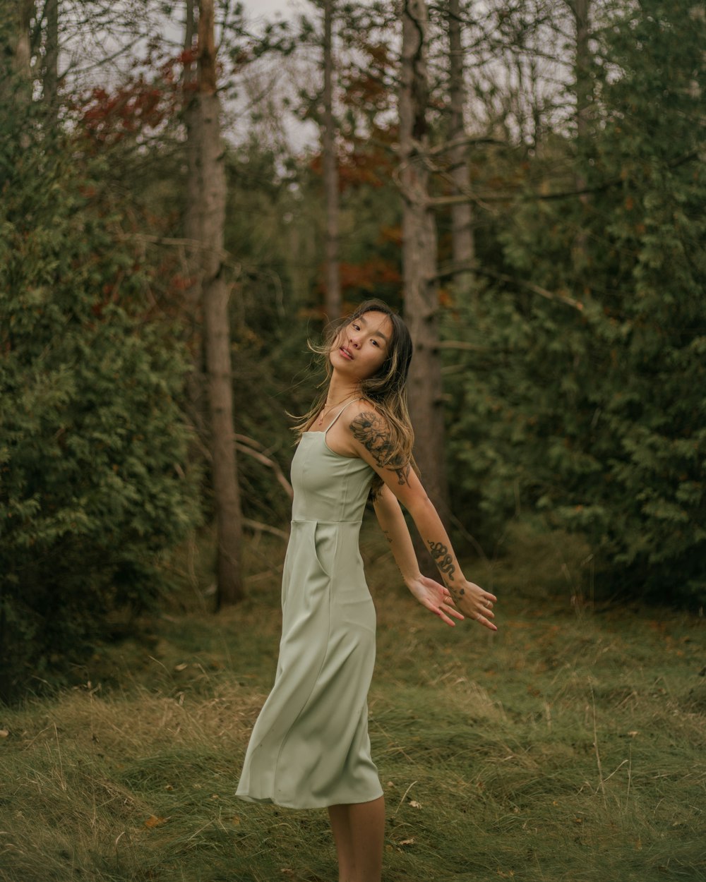 a woman in a green dress standing in a forest