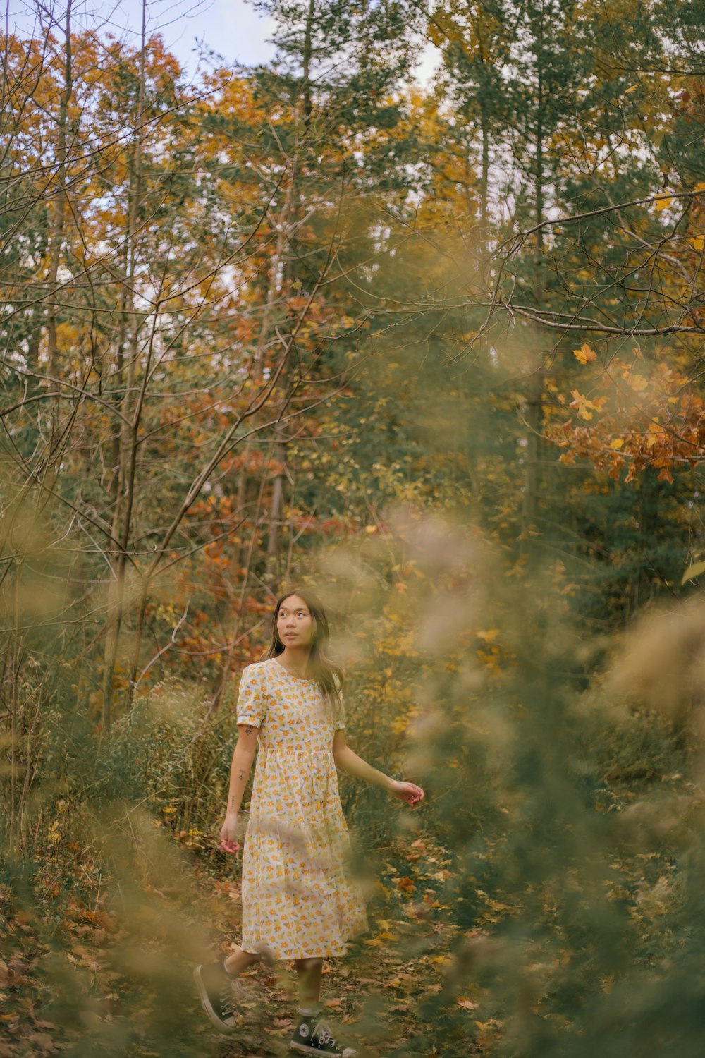 uma mulher em um vestido amarelo andando através de uma floresta