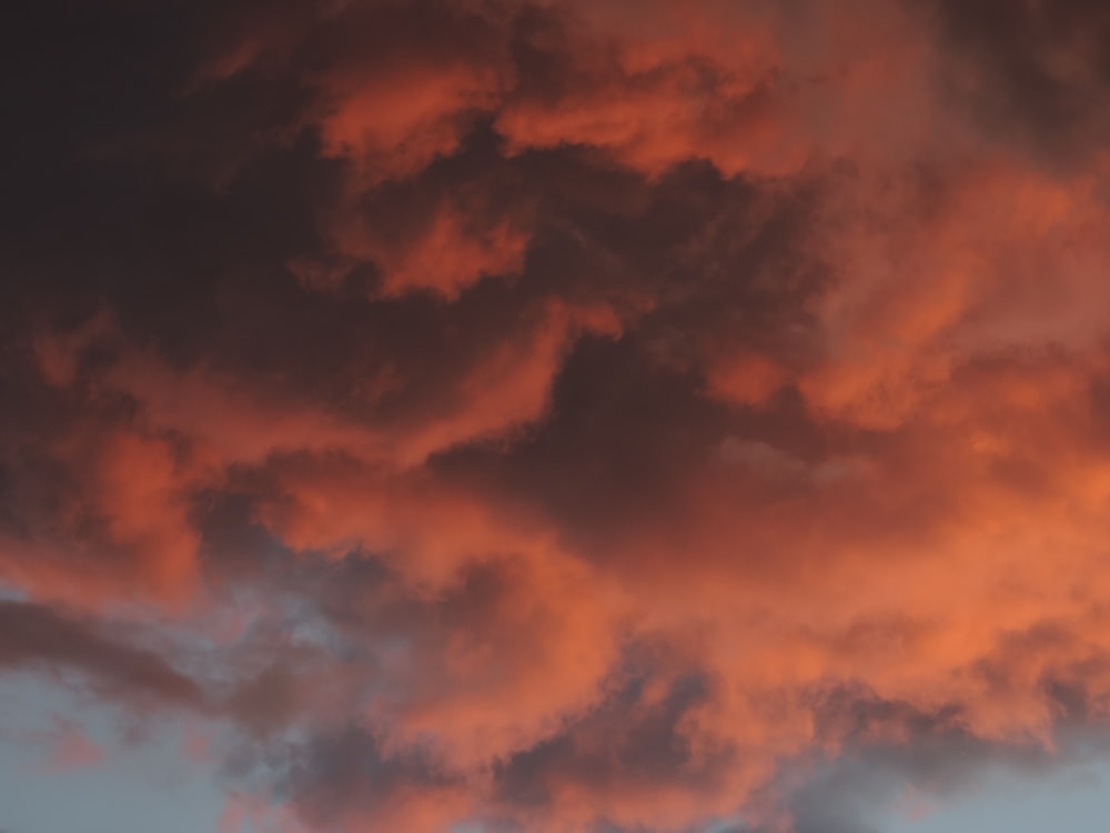 a plane flying through a cloudy sky at sunset