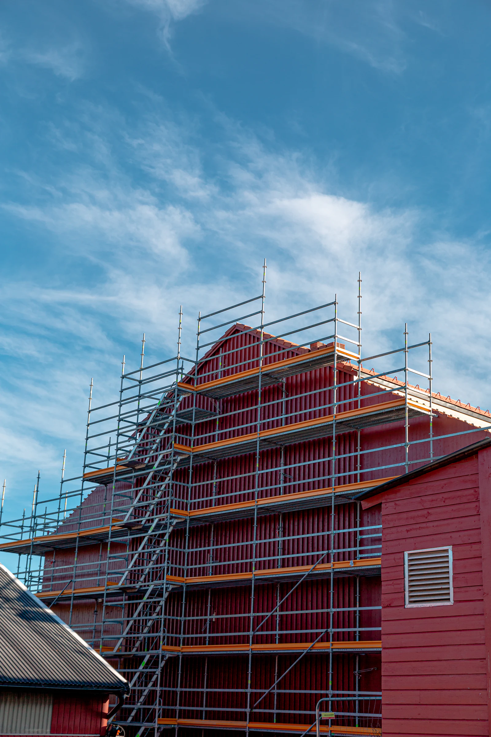 A house wrapped in scaffolding under a blue sky