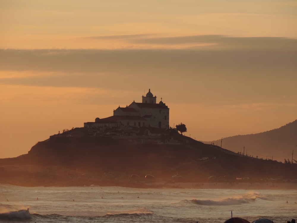 a large building sitting on top of a hill next to the ocean